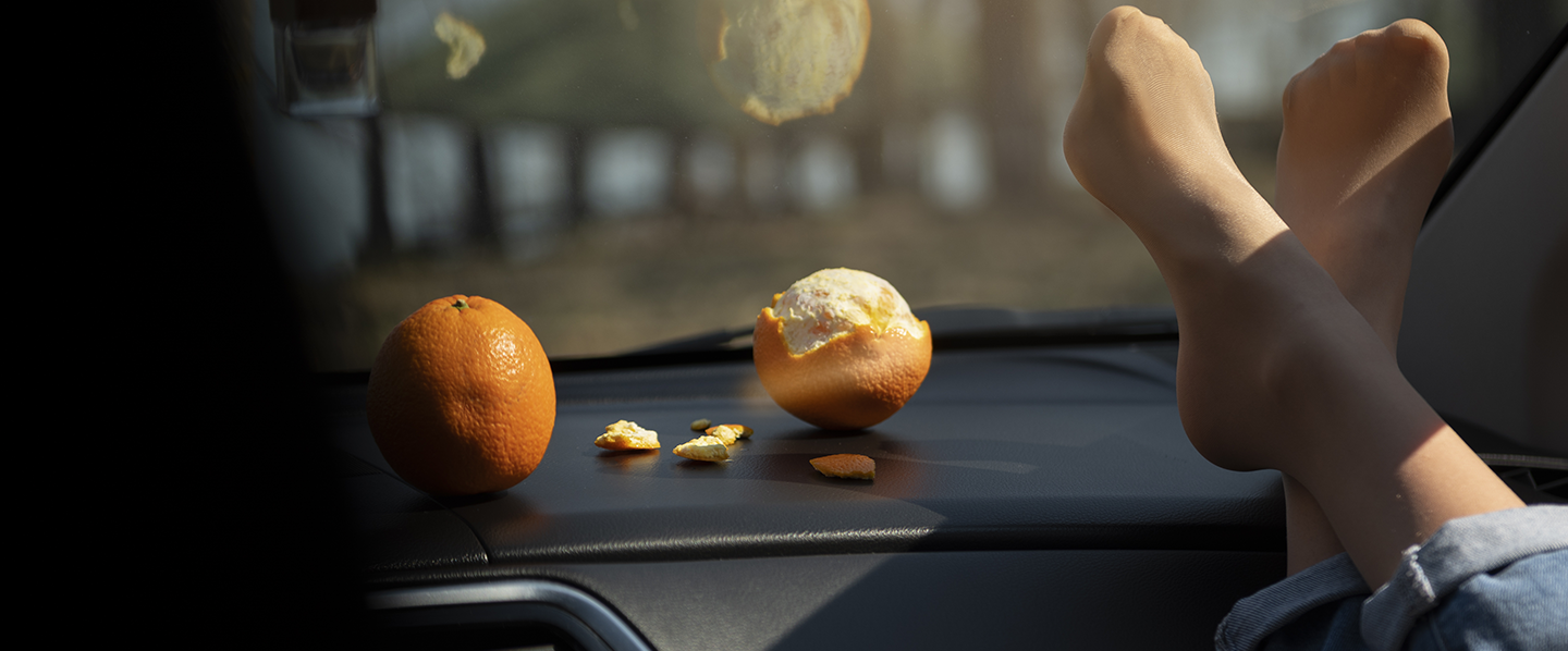 Imagem de uma pessoa dentro de um carro e duas laranjas